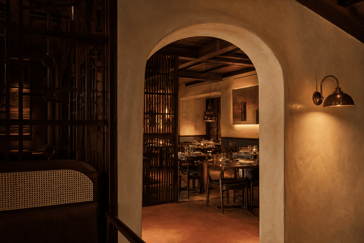 A plaster arch and teak screen leading into the dining room